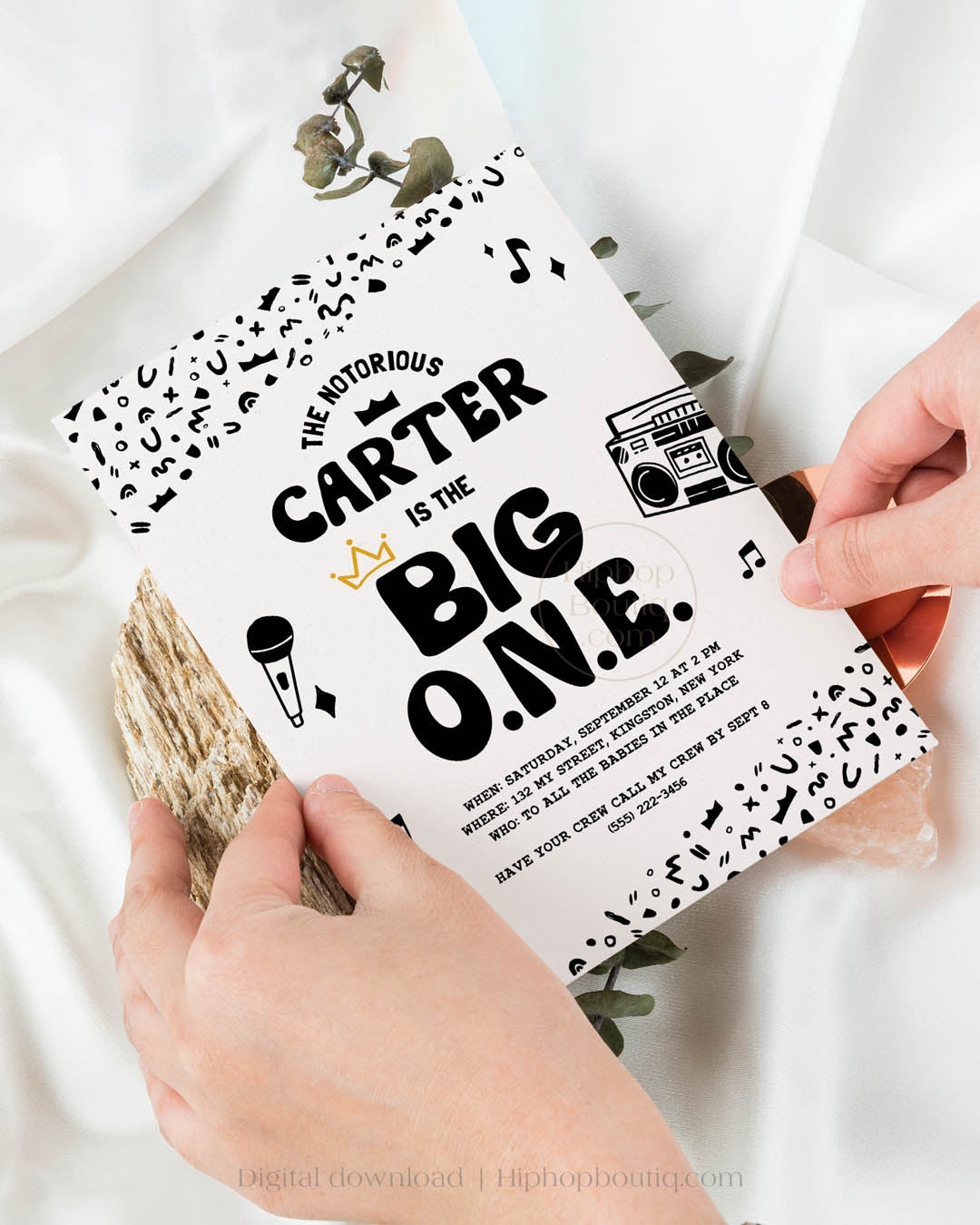 Hip-hop themed, printed birthday invitation card. The card features an editable 'The Big One' design including a customizable child's name. The card also features a black and white squiggly pattern, 90s rap-themed illustrations, and a golden crown.