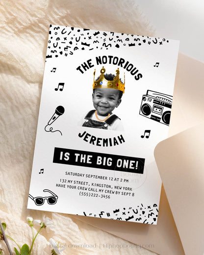 Hip-hop themed, printed birthday invitation card. The card features an editable 'Notorious One' design with a black and white squiggly pattern, and an image of a happy child wearing a crown and a gold chain.